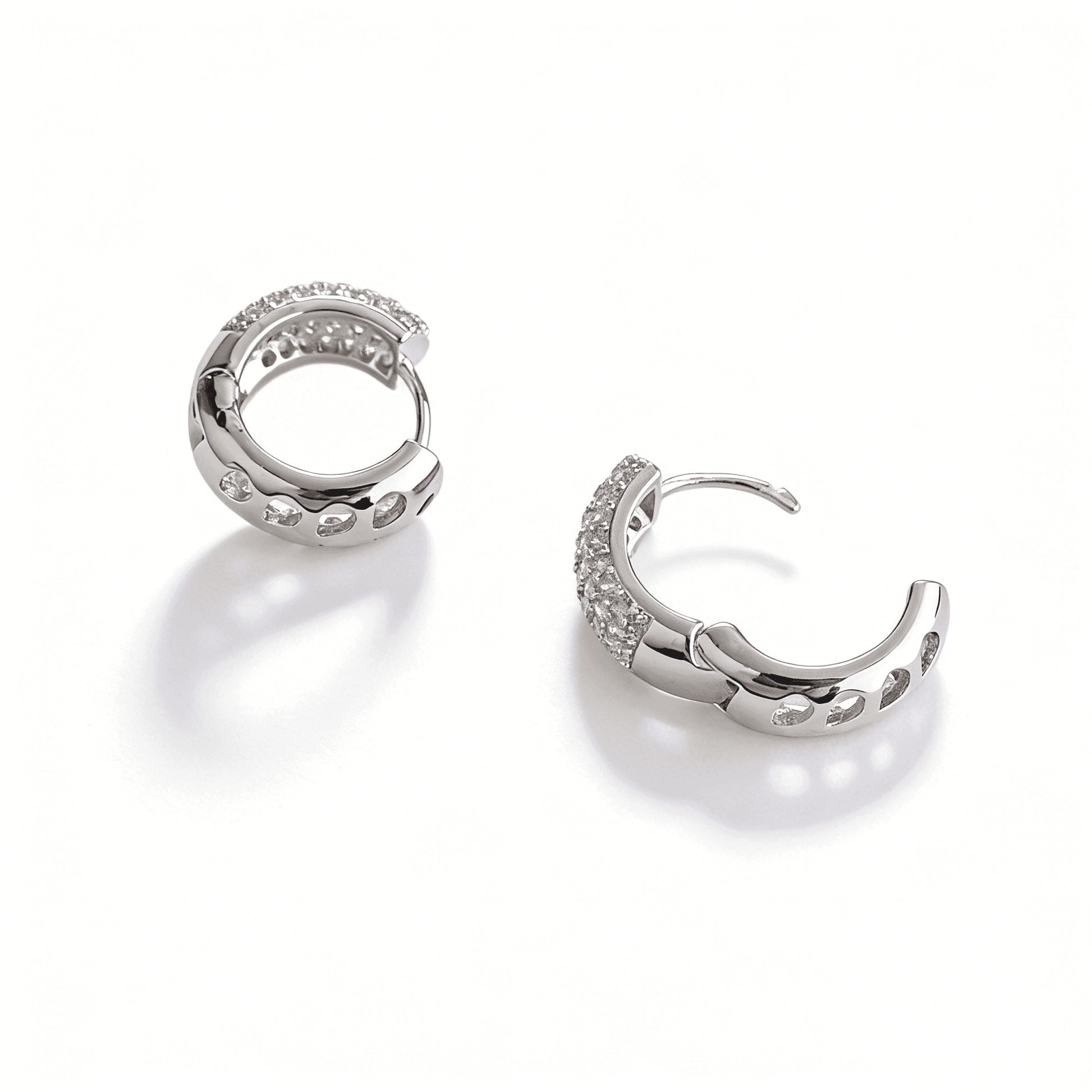 Side profile of silver huggie hoop earrings highlighting the modern hollowed-out design and high-shine finish.