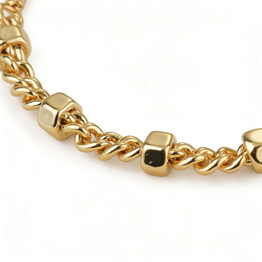 Close-up of an 18k gold plated snake chain bracelet with a polished hex nut hardware connector.