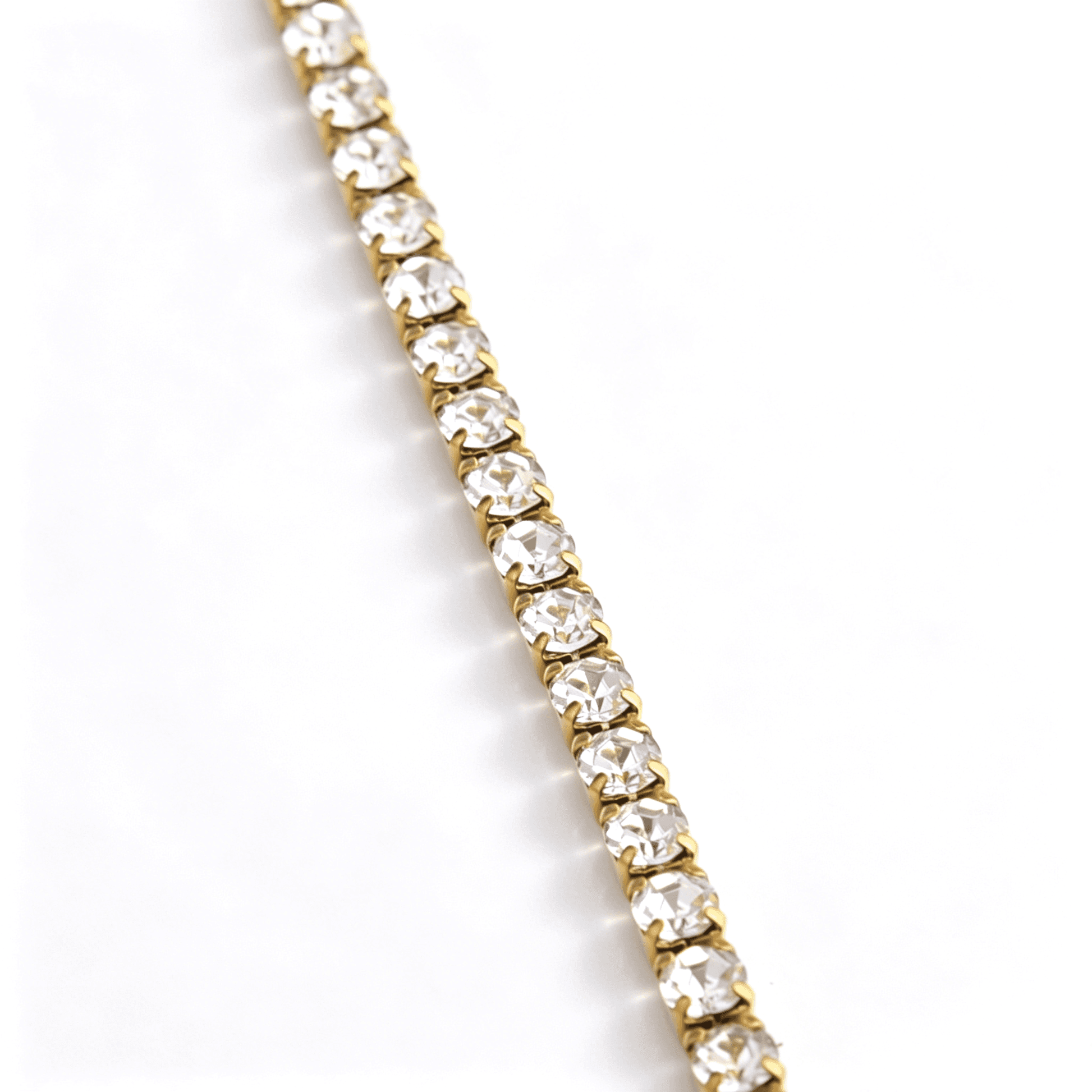 Macro detail of clear round stones held in gold-tone four-prong settings