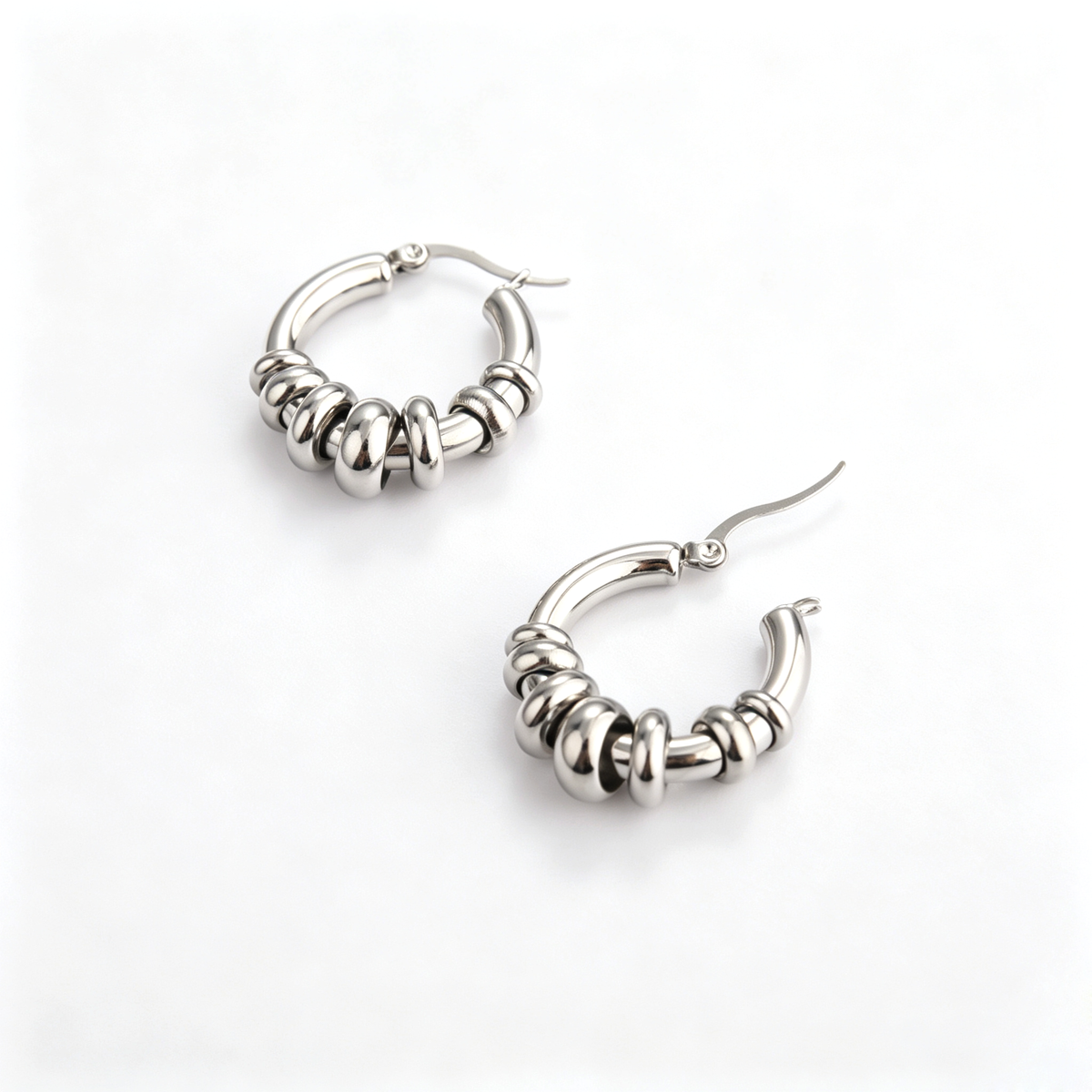 Side perspective of the silver hoop earrings with one latch post unclasped showing structure.