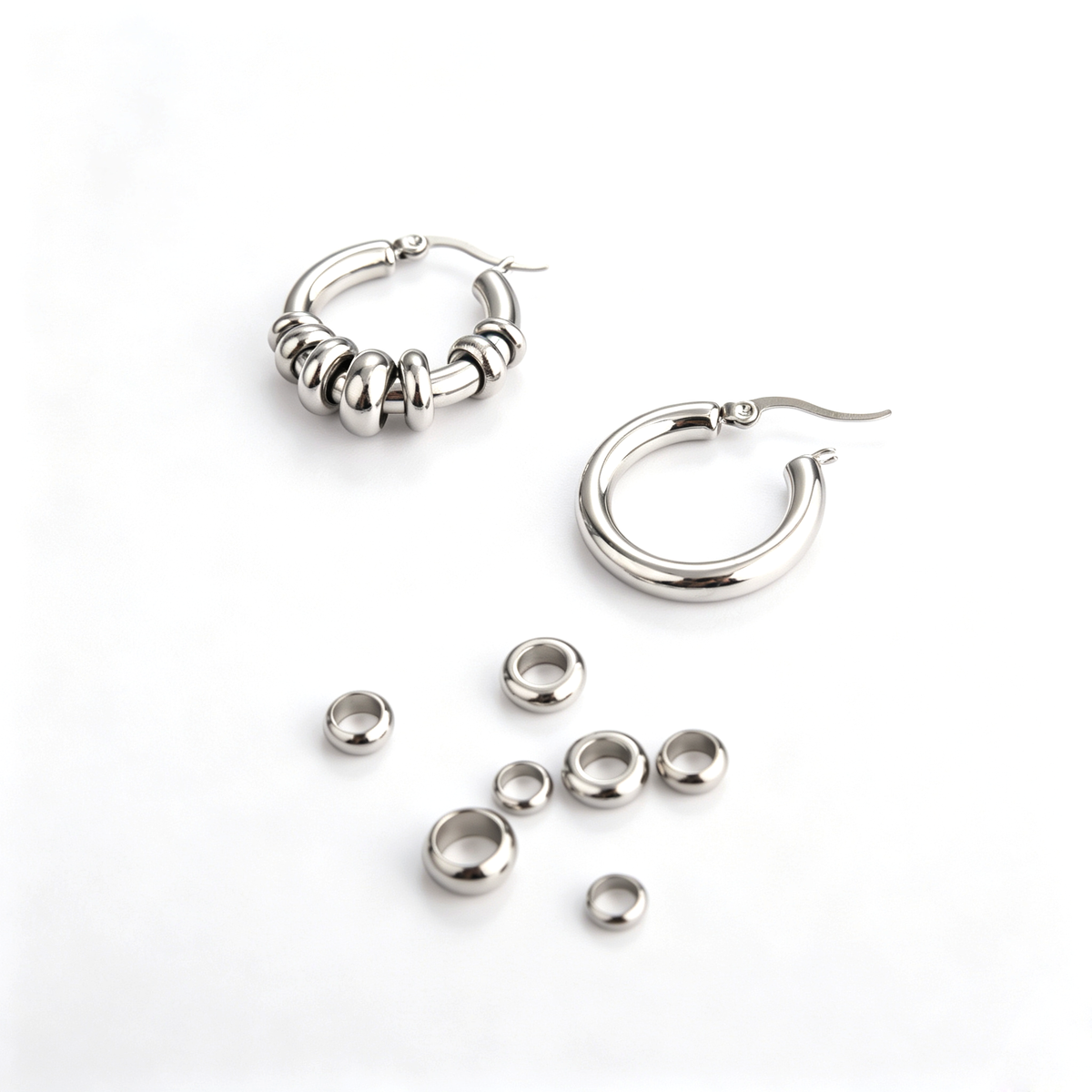 Display showing one plain hoop earring next to the detached multi-sized sliding metal ring beads.