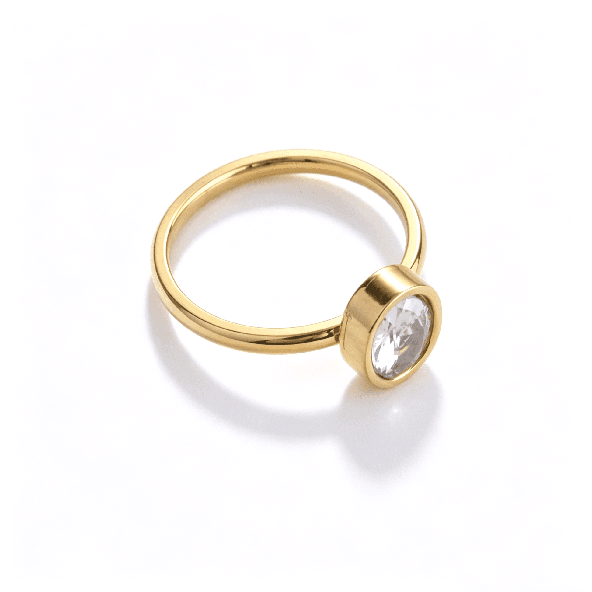 High angle view of a minimalist gold tone stainless steel ring with a clear oval zircon stone.