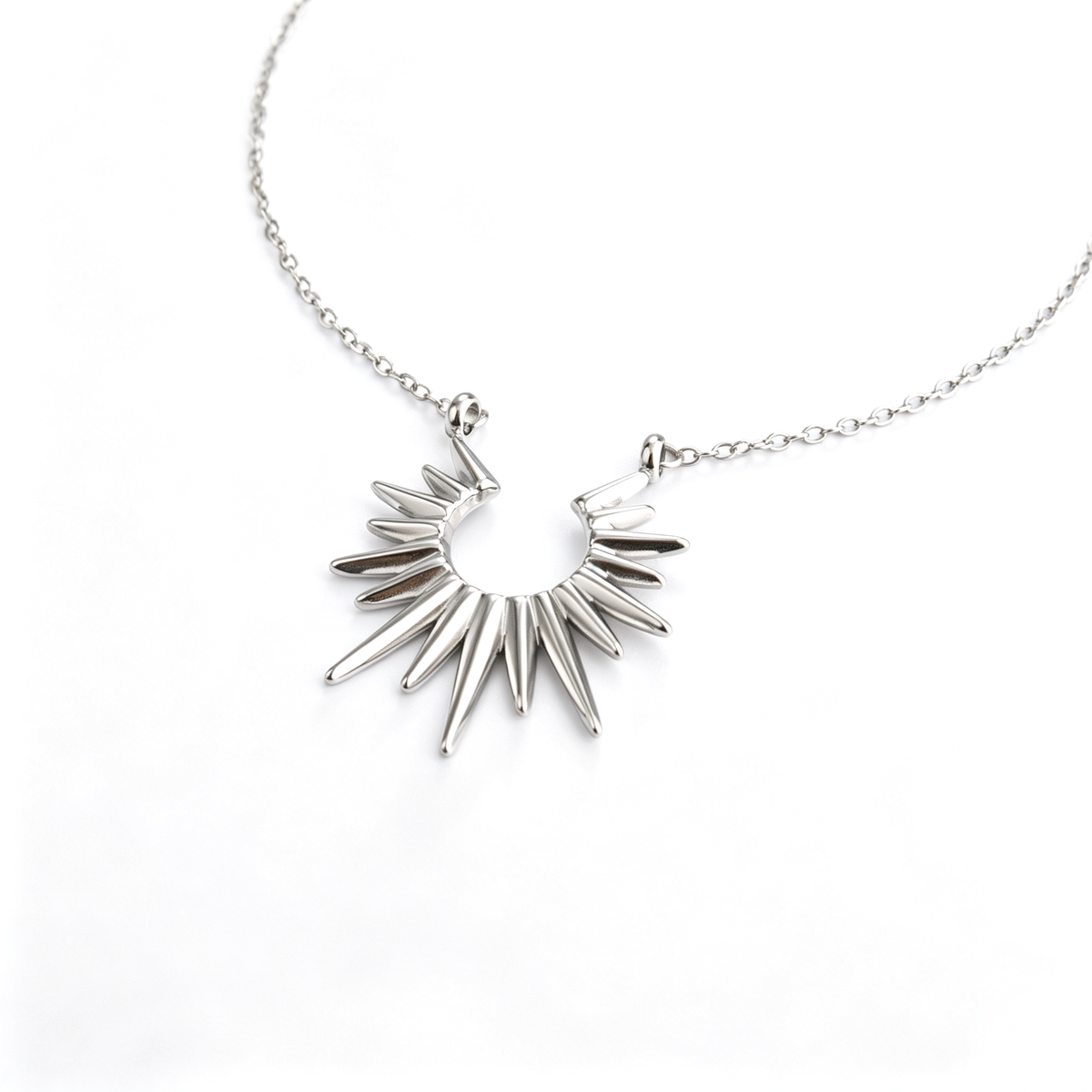 Angled close-up of the silver-tone crescent sunburst spike pendant attached to a curb chain.