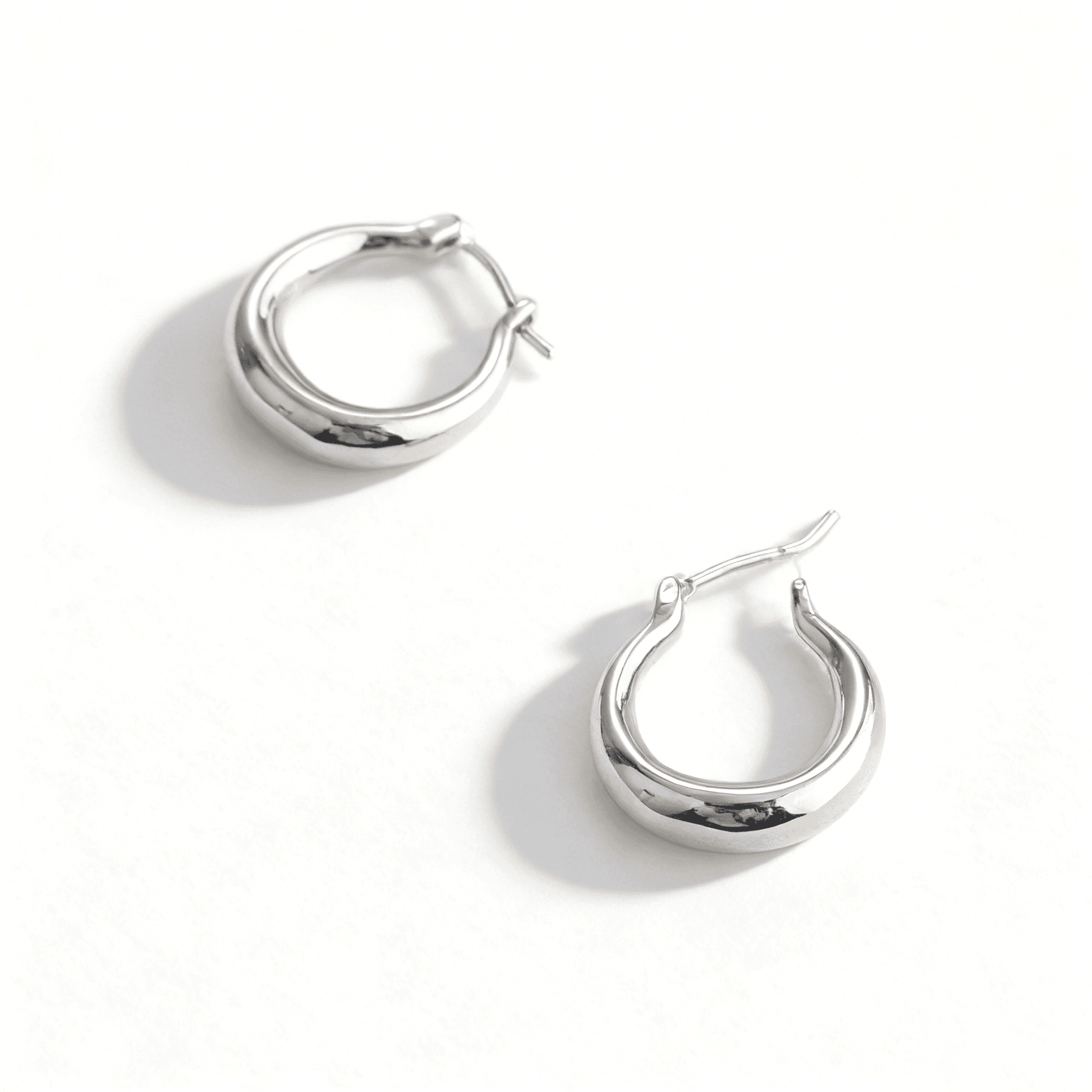 Close-up of textured silver earrings with an irregular, organic shape and high-shine molten finish.