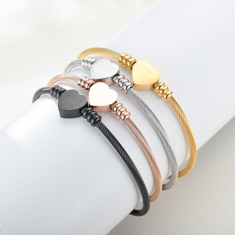 Gold, silver, and rose-tone heart cuff bracelets displayed together on a wrist.