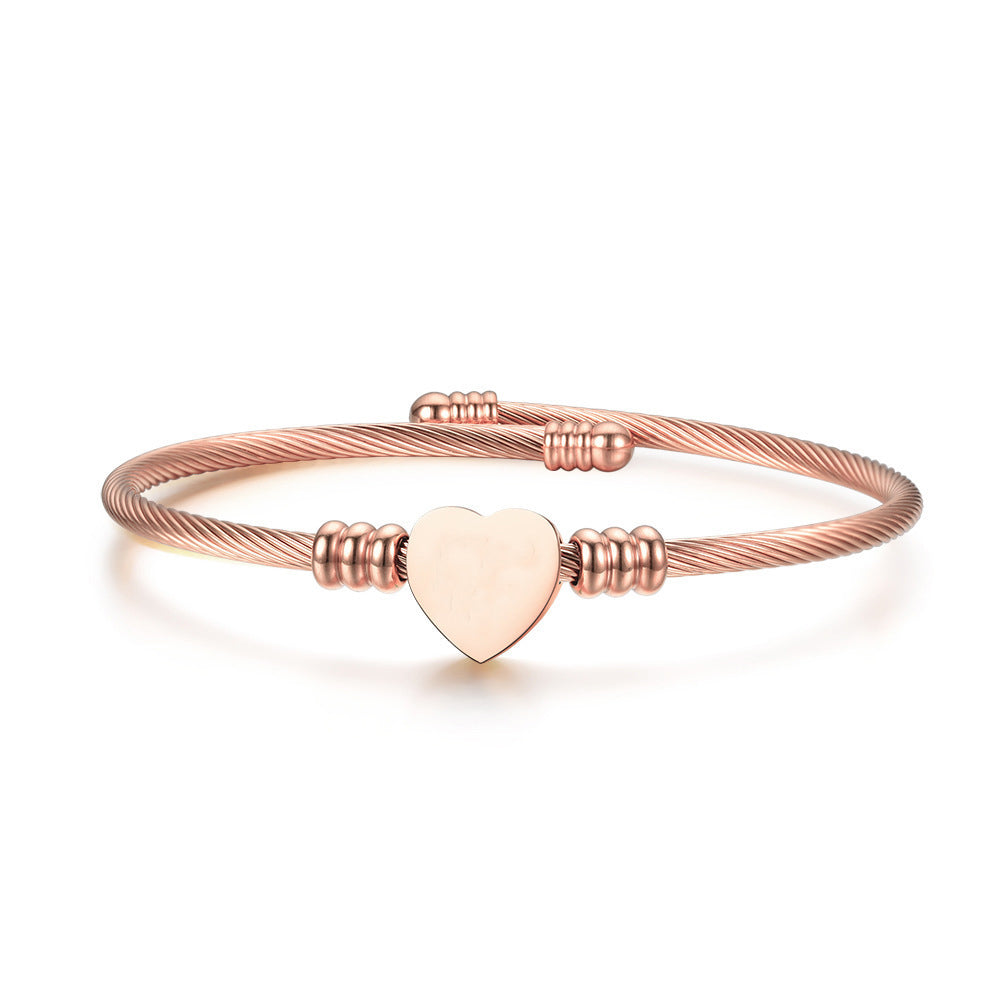 Rose-tone heart cuff bracelet shown from a low side angle, highlighting its slim open band.