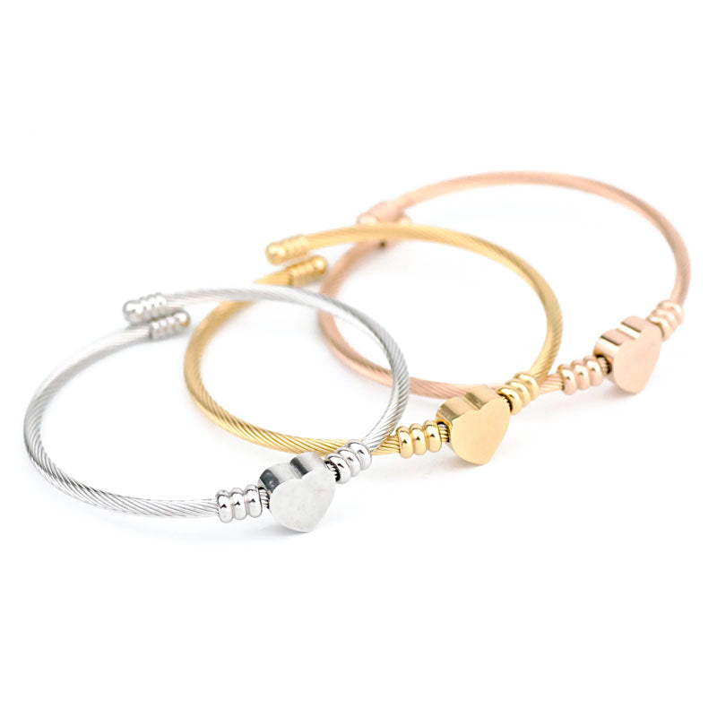 Heart cuff bracelets in gold, silver, rose, and black tones arranged together to compare color options.