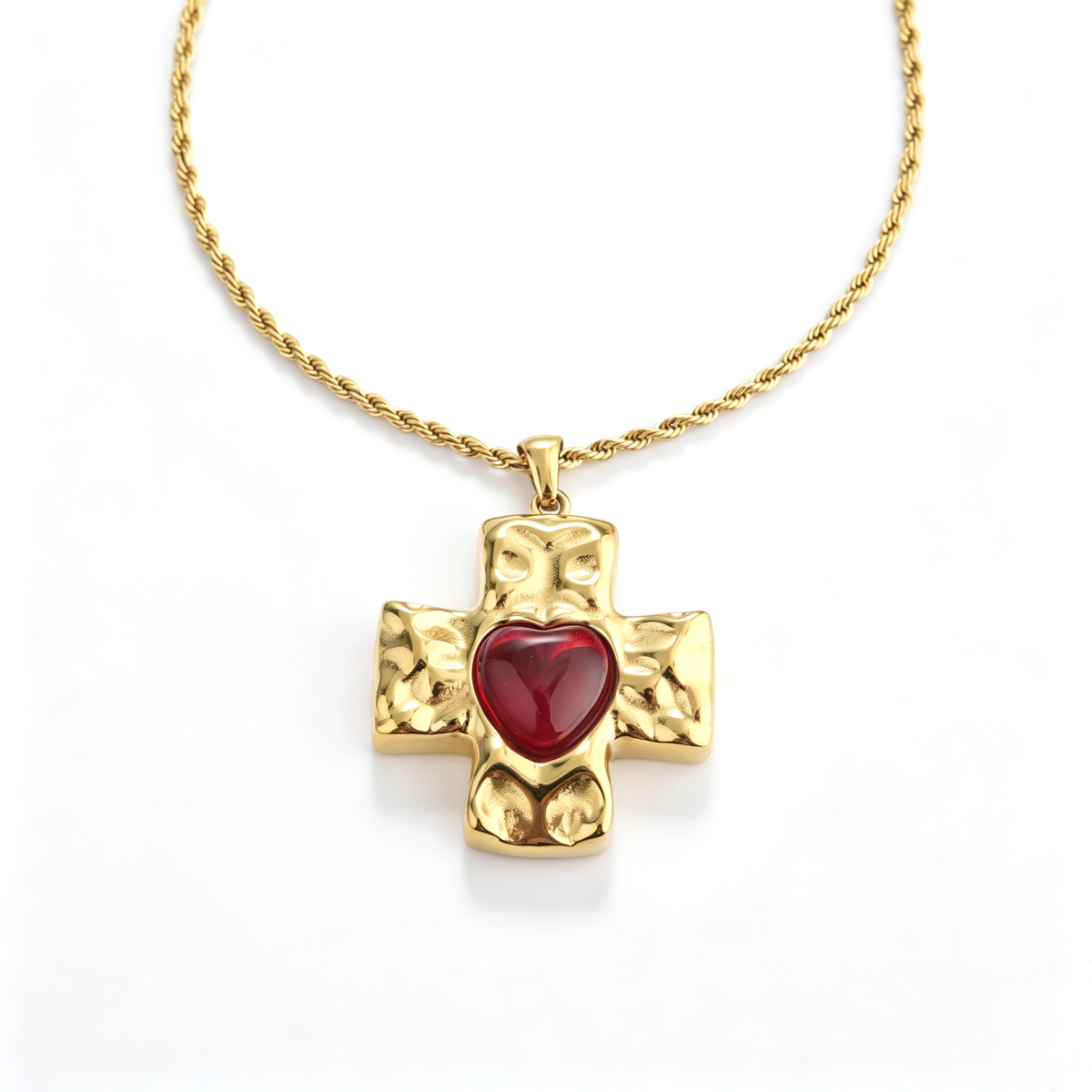 Front perspective of a chunky gold-plated Byzantine cross pendant with a red heart-shaped gemstone.