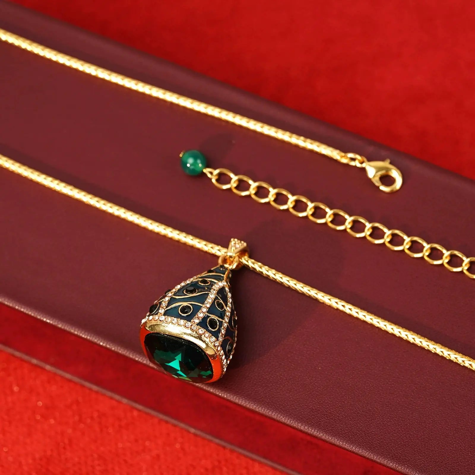 Macro view of the magnificent emerald-green teardrop crystal base beneath the micro-paved rhinestones egg charm.