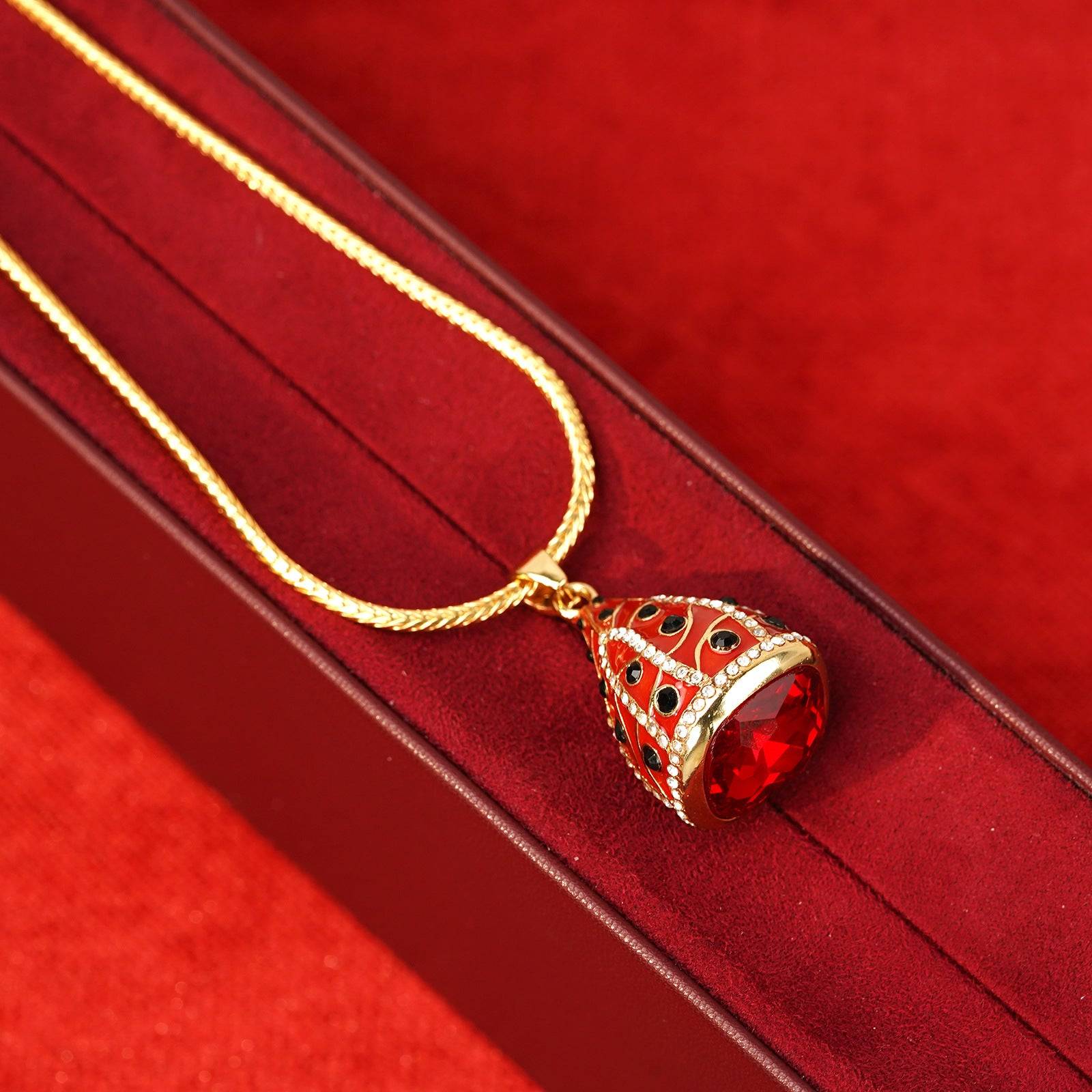 Angled close-up of the ruby-red teardrop crystal base and premium real gold-plated copper alloy casing.