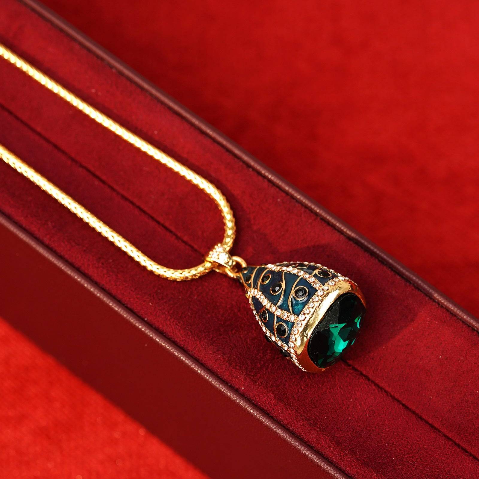 Close-up texture of the detailed teal-blue enamel work accented with clear pavé crystals and black cabochon gems.