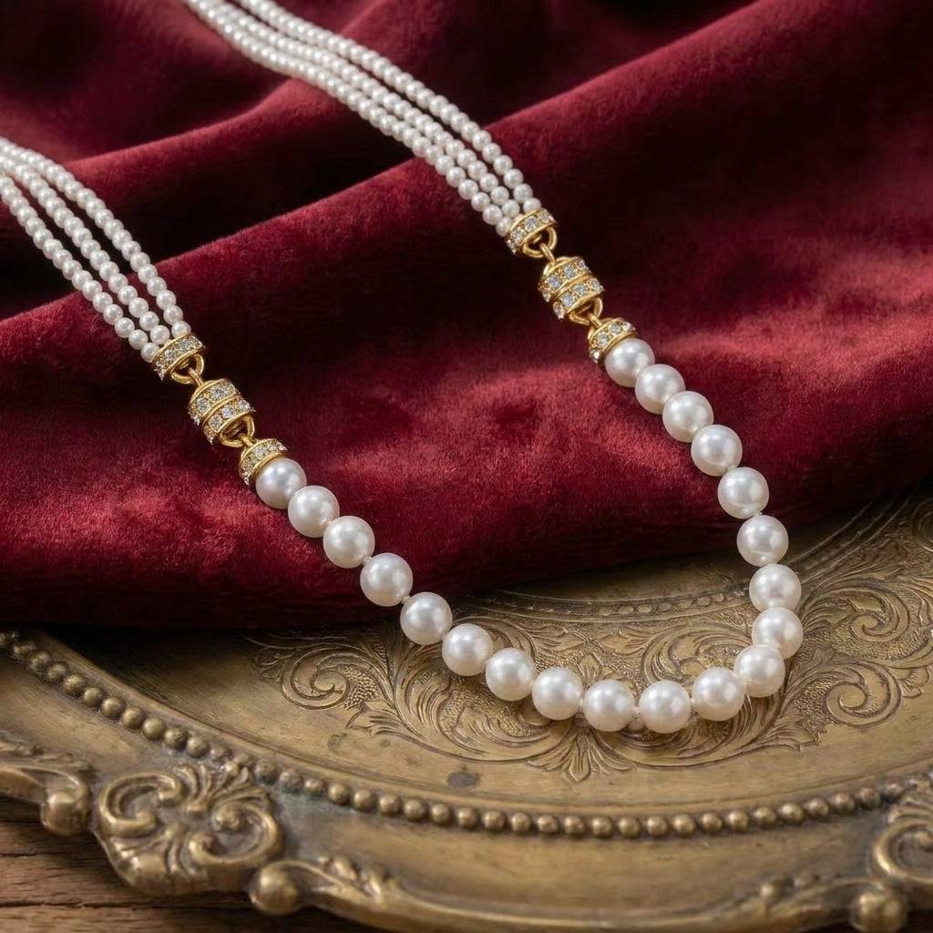 Elegant close-up of the white French vintage multi-strand pearl necklace draped over rich burgundy velvet and an antique brass tray.