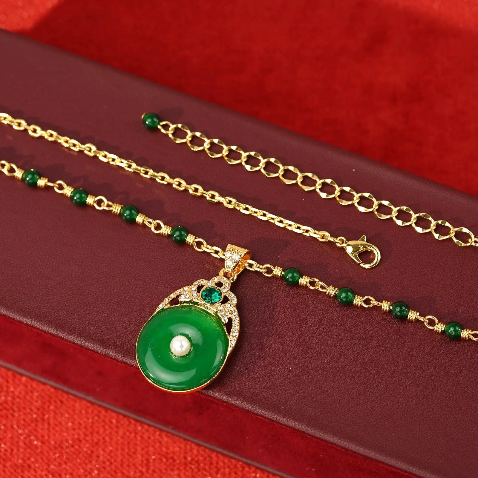 Close-up of the adjustable real gold-plated lobster clasp and the delicate green beaded accent chain on a luxury display box.