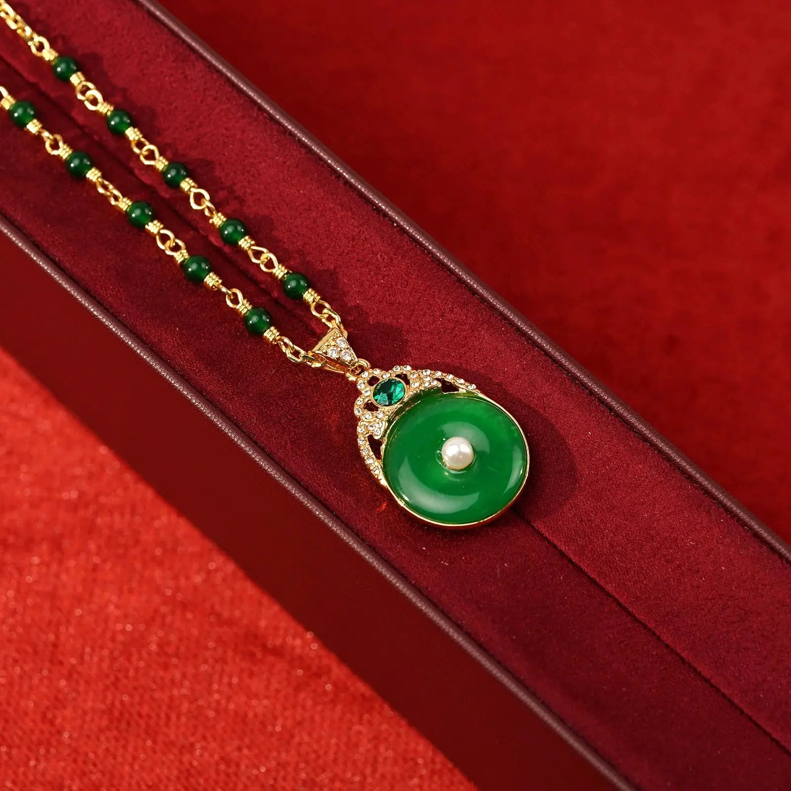 Macro details of the heavy gold-plated copper crown charm micro-paved with clear rhinestones holding the rich green jade-style chalcedony disc.