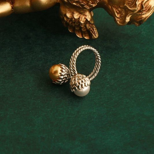 Vintage gold pinecone pearl Toi et Moi statement ring displayed next to a classical golden cupid cherub statue base.
