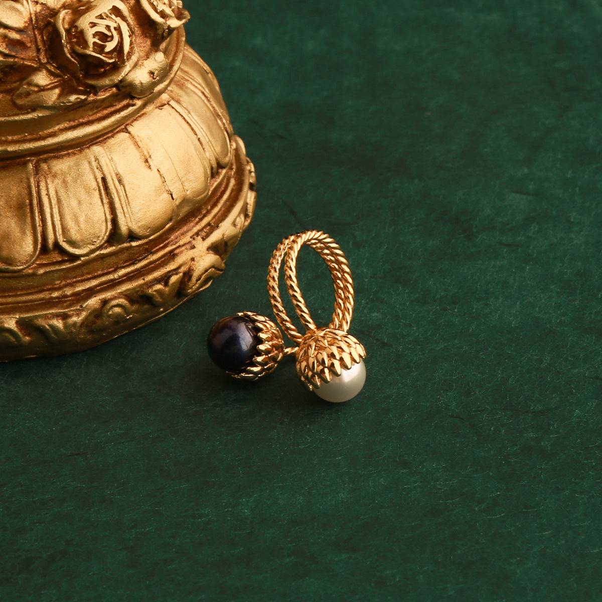 Close-up of the botanical gold-plated pinecone ring showing intricate carved metal scales holding high-luster white and black pearls.