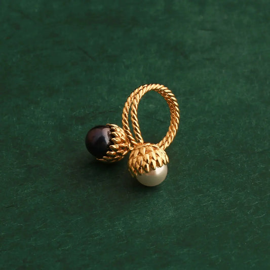 Side view of the copper alloy gold pinecone bypass ring, showcasing the sculptural layout and contrast of the white and black pearl duo.