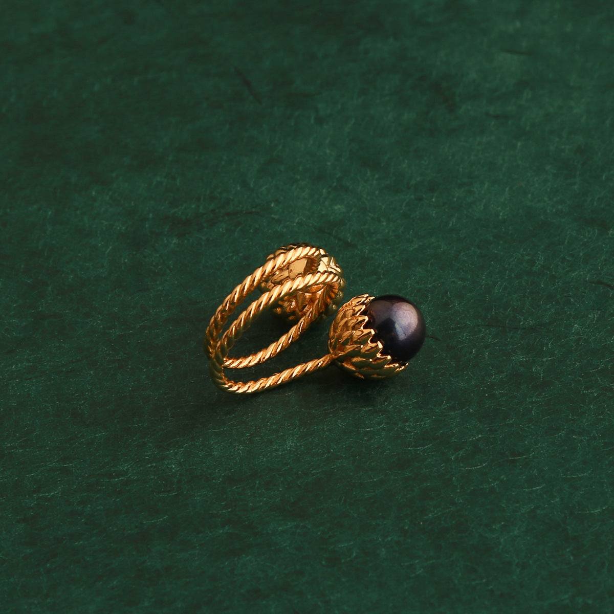 Vintage platinum-tone silver pinecone bypass ring with contrasting gold and white pearls, styled under an antique golden statue wing.