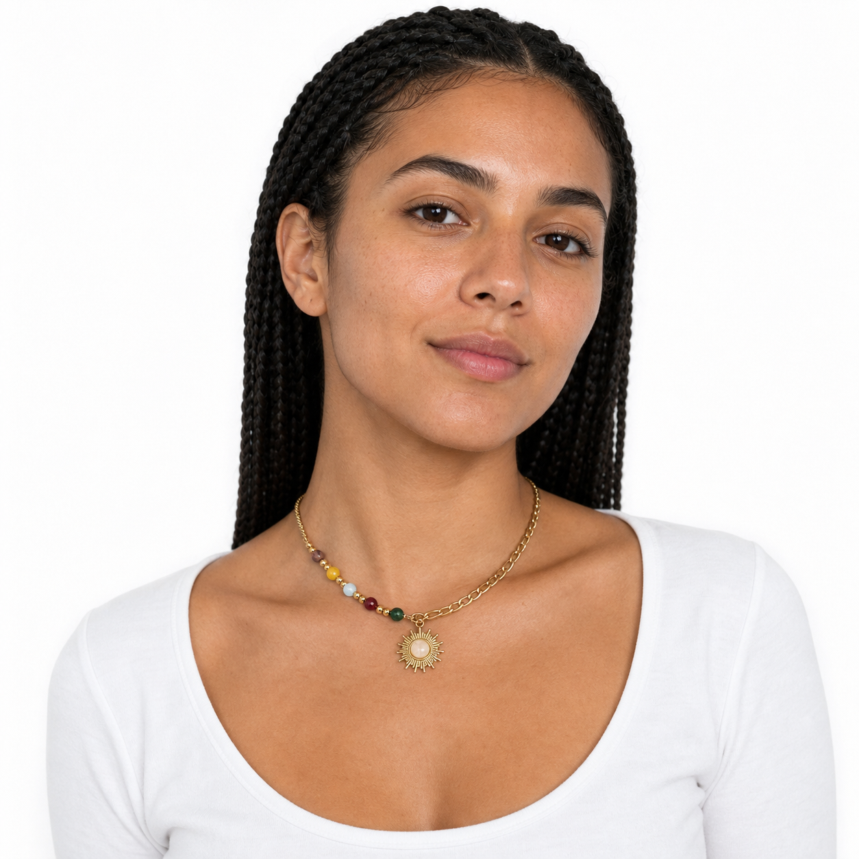 Young woman wearing a gold sun pendant necklace with colorful beads in a white studio.