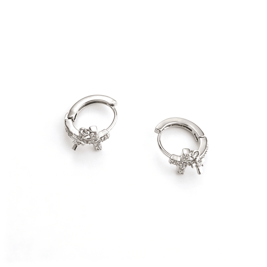 Flat lay of Y2K silver double cross drop charm huggie earrings highlighting the micro-paved crystal cross and the swinging mini dangling charm.